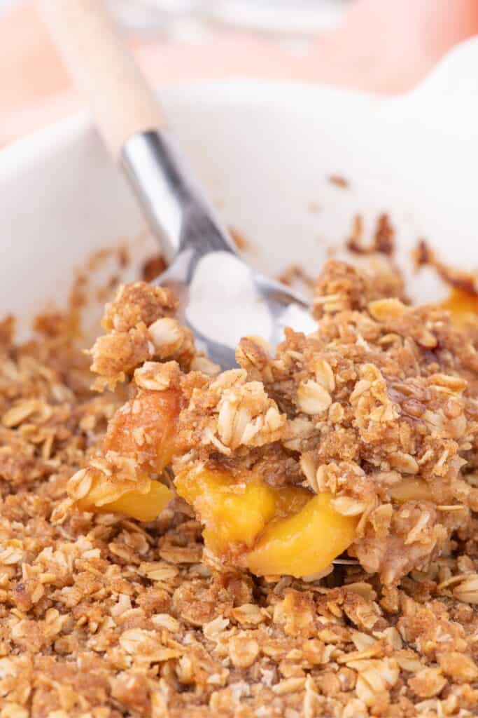 scooping up a serving of the best peach and oatmeal crumble