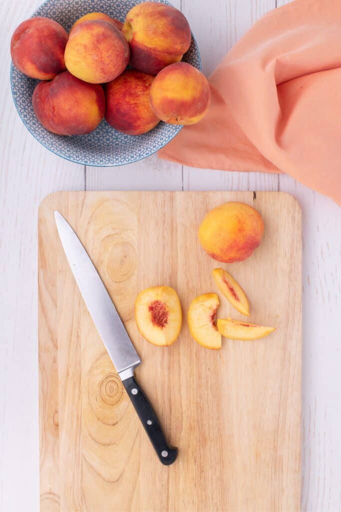 slicing unpeeled peaches and adding to glass bowl