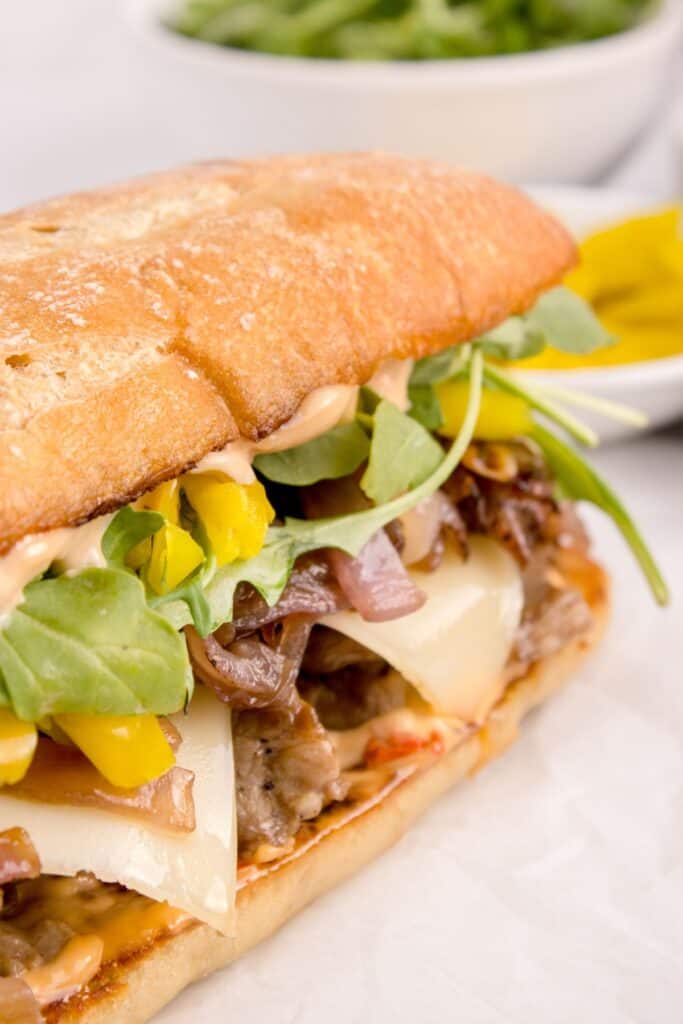 closed steak sandwich with toppings