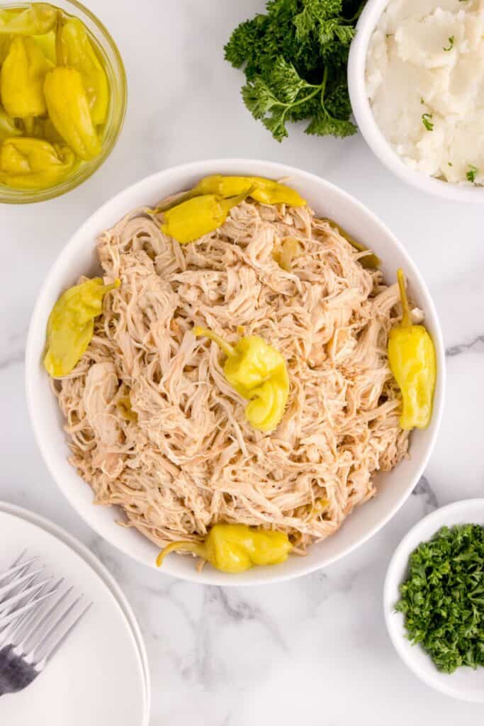 mississippi chicken in a bowl with pepperoncini peppers, parsley, and mashed potatoes