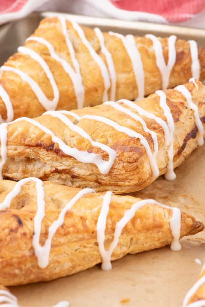 Close up image of three baked and iced apple turnovers.