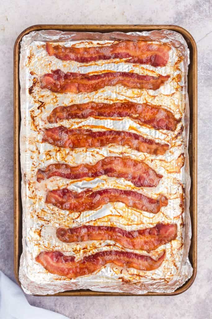 overhead view of baked bacon on a baking sheet covered in aluminum foil.