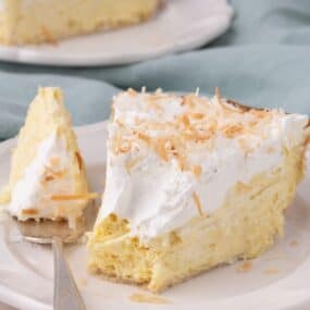 Forkful of coconut cream pie on a white plate with a cross section view of the layers of the pie.