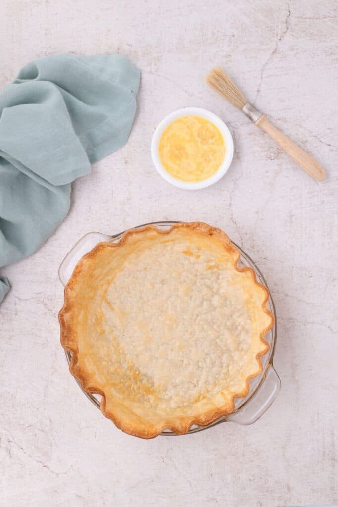 Baked pie crust with whipped egg and basting brush.