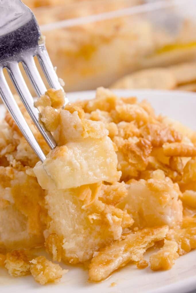 White plate with pineapple casserole and a fork.