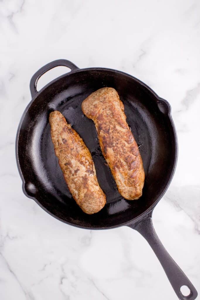 Two pork tenderloins cooked in a cast iron pan.