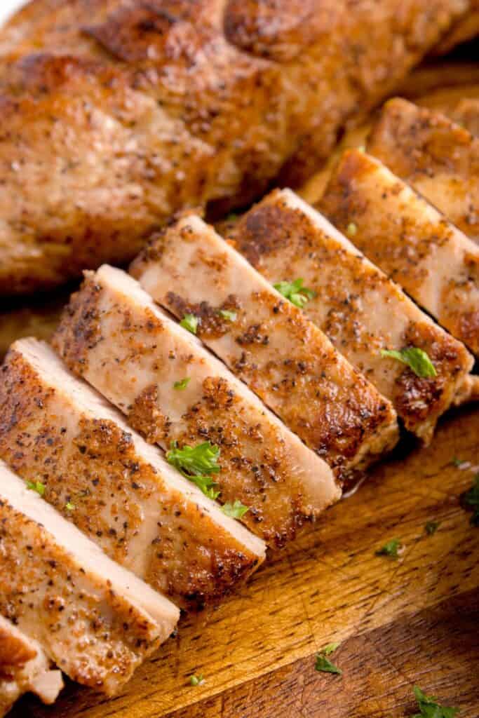 Two cooked and sliced pork tenderloin, garnished with parsley.