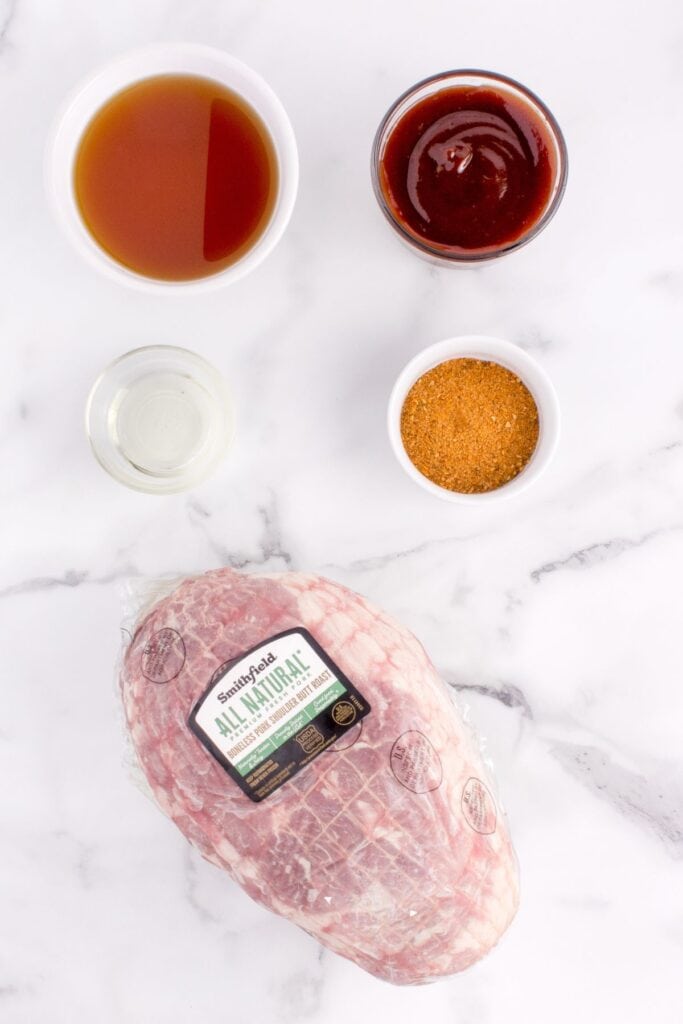 ingredient lay out of packaged pork shoulder, chicken broth, BBQ sauce, olive oil, and Famous Dave's dry rub seasoning.