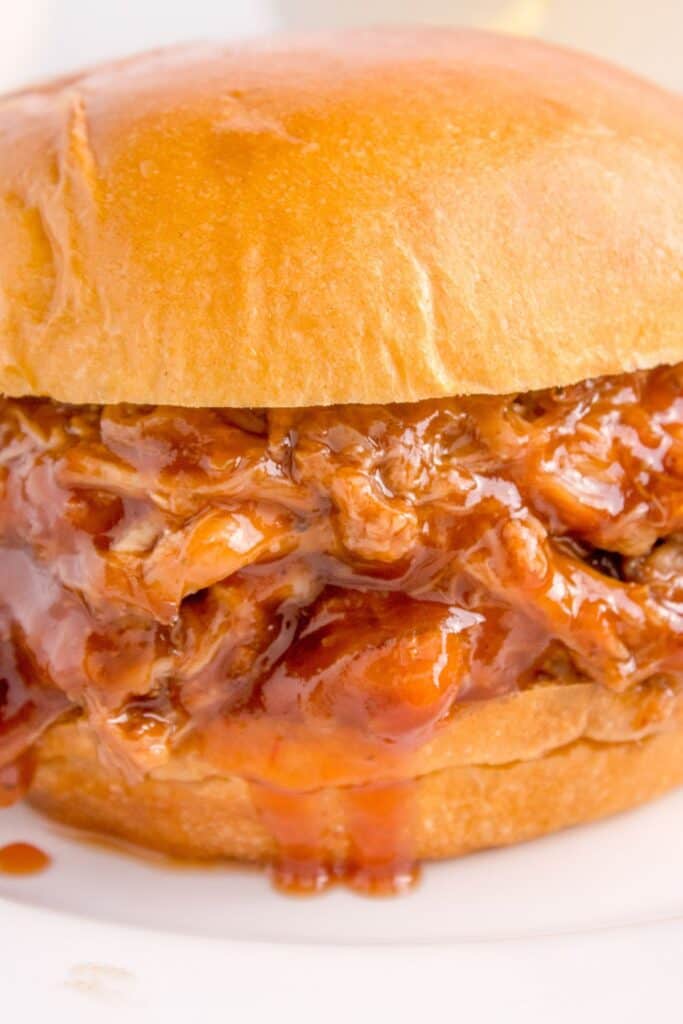 close up image of pulled pork with BBQ sauce in a bun.