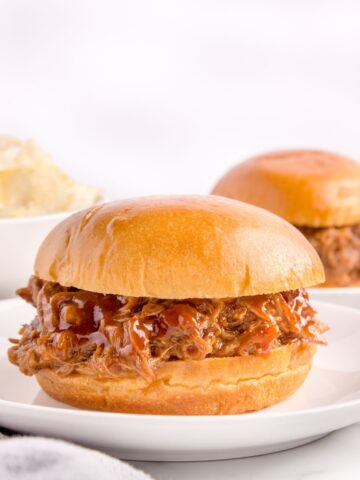 Pulled pork on a plate with BBQ sauce in a bun