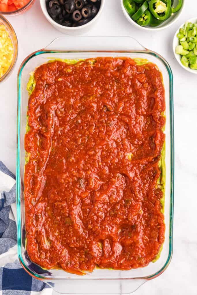 Spread salsa as the fourth layer of 7 layer dip.