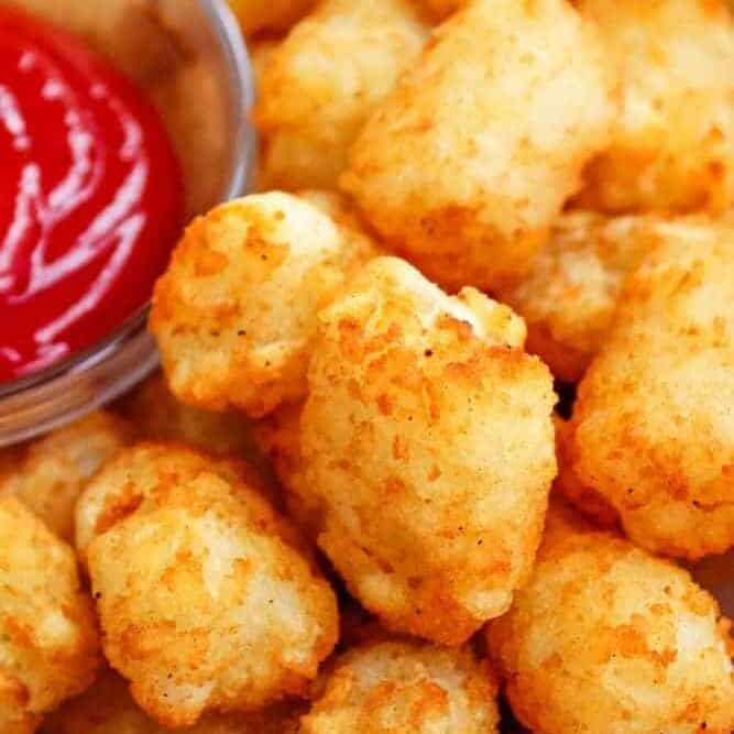 Closeup of Air Fryer Tater Tots with bowl of ketchup peaking into the top left