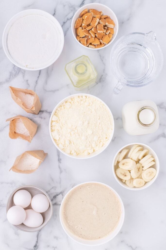 Ingredients for banana pudding cake: yellow cake mix, banana pudding, eggs, water, vegetable oil, vanilla pudding, milk, Cool Whip, Nilla cookies, and bananas.