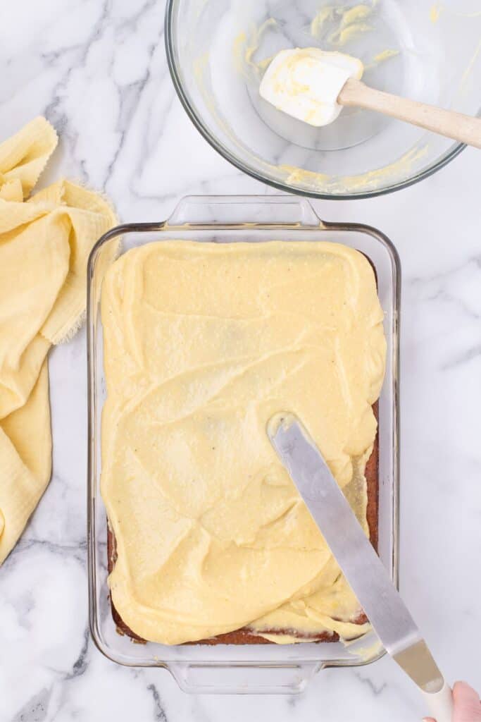 Cake with offset spatula spreading banana pudding on top.