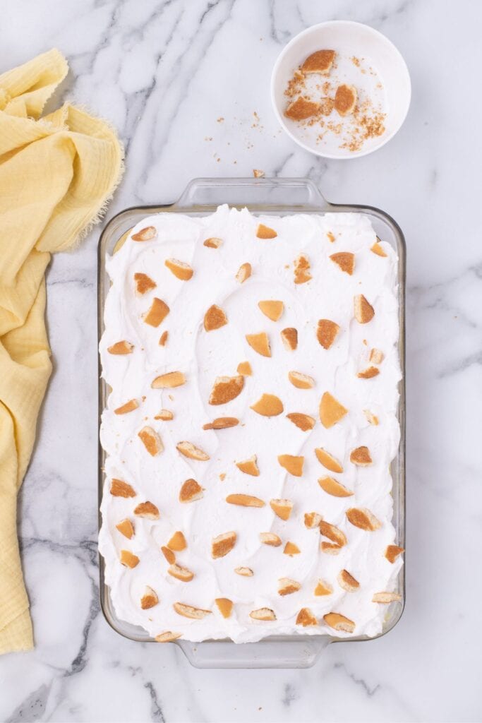 banana pudding cake topped with whipped topping and nilla wafers.