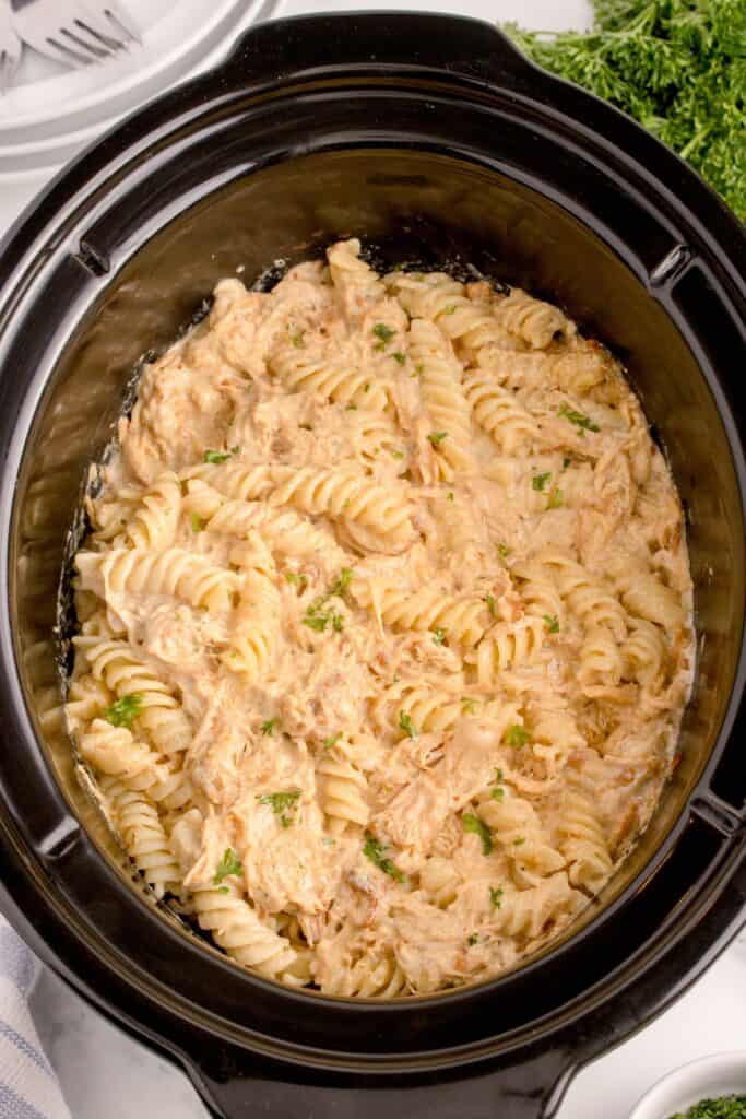 Garlic Parmesan Chicken and Pasta in a crockpot with parsley garnish.