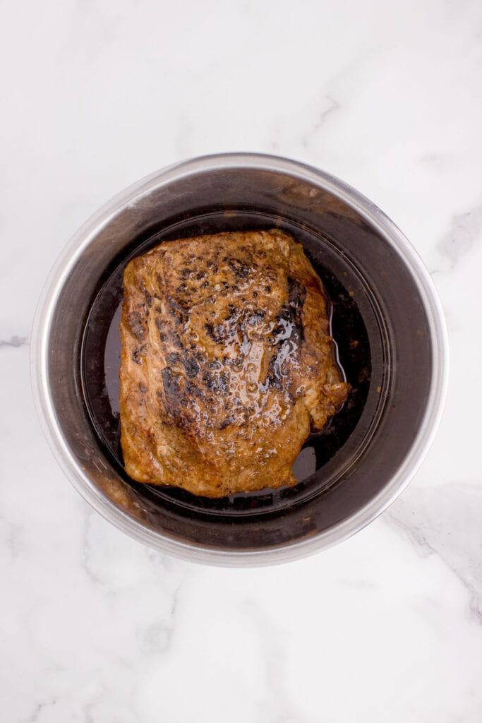 Overhead view of Instant Pot insert with cooked pork tenderloin and juices.