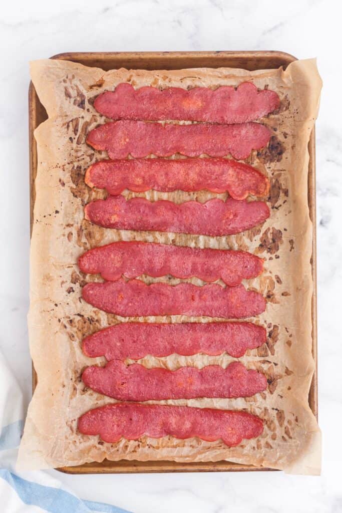 Cooked turkey bacon on a parchment covered baking sheet.