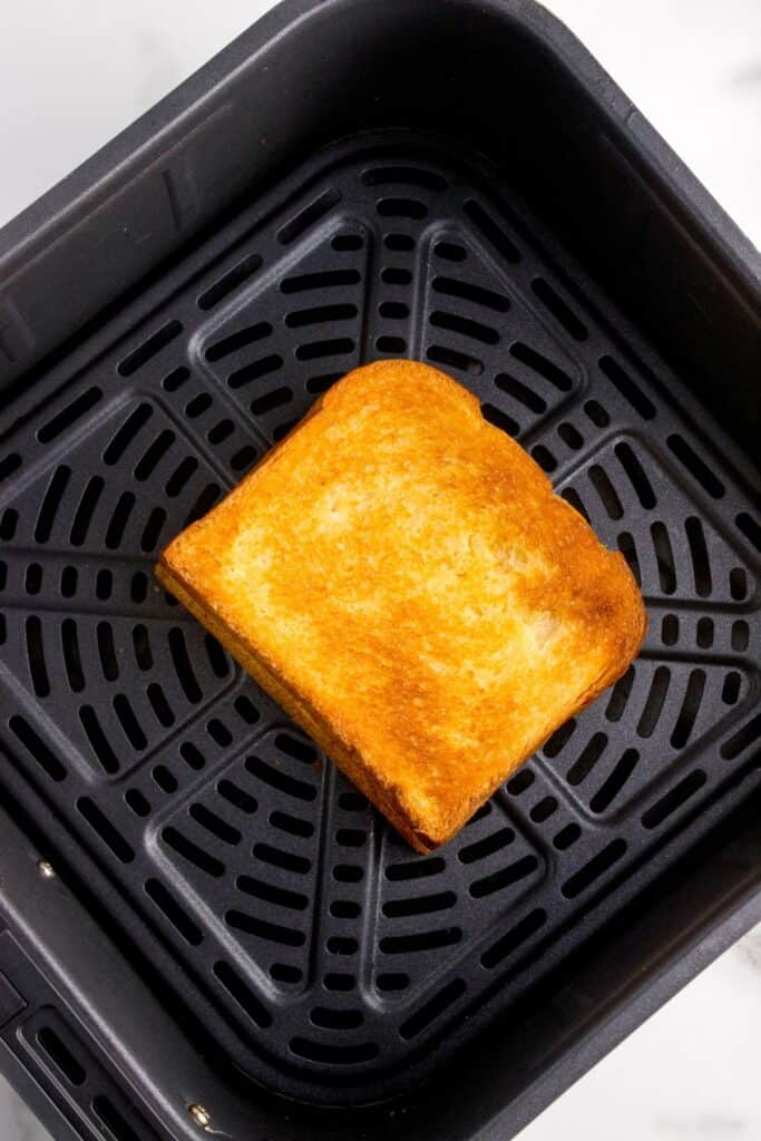 Cooked grilled cheese in an air fryer basket.