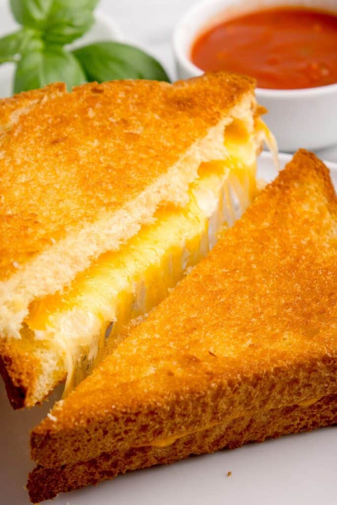 Close up of an air fryer grilled cheese cut in half with cheese coming out.