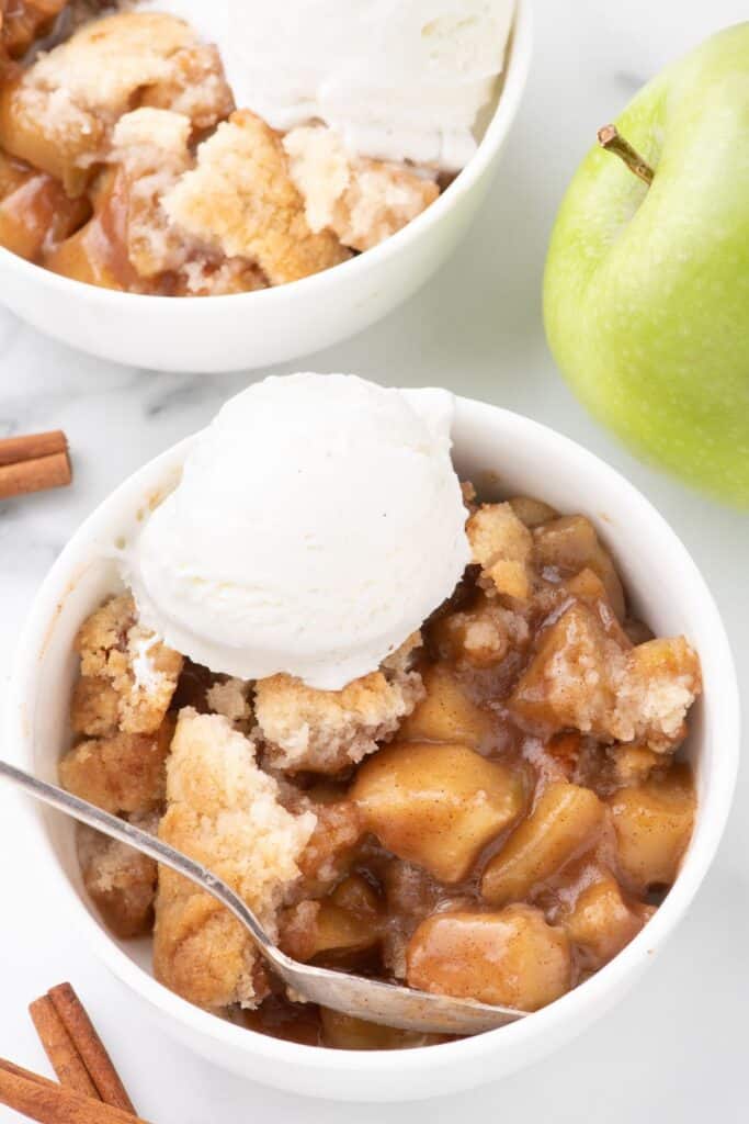 Overhead image of two bowls of apple cobbler with ice cream on top.