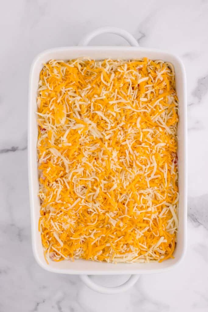 Chicken tetrazzini in a baking dish with shredded cheese on top.