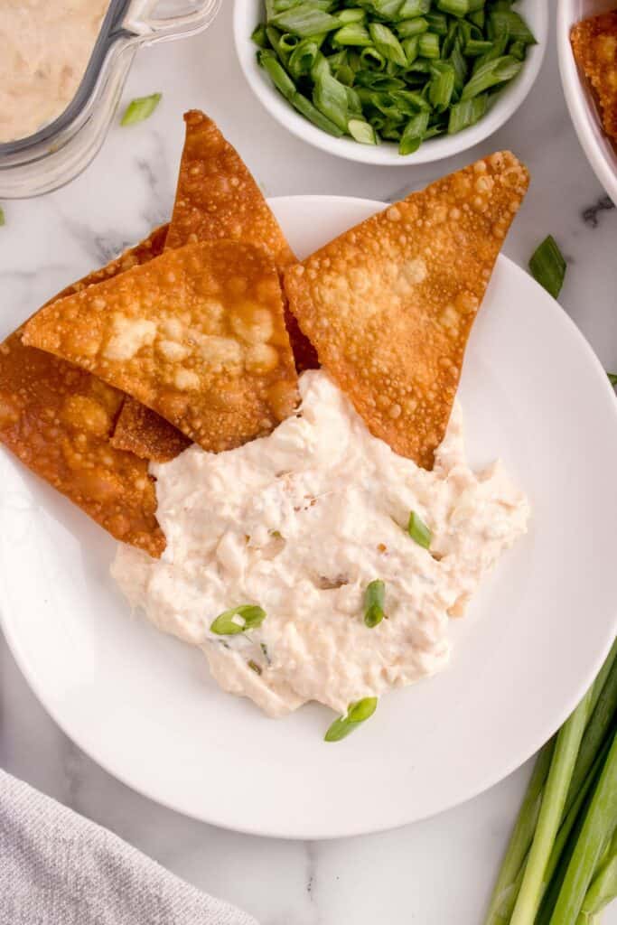 White dish of crab rangoon dip with wonton chips on the side.