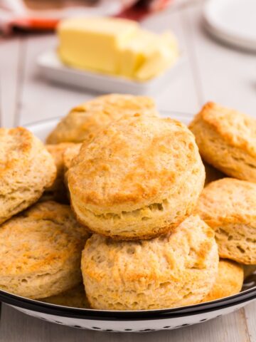 Baked biscuits piled up in a low serving bowl on a dinner table.