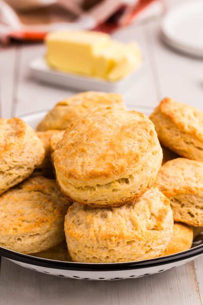 Baked biscuits piled up in a low serving bowl on a dinner table.