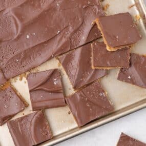 Saltine cracker toffee on baking tray, partially sliced into squares.