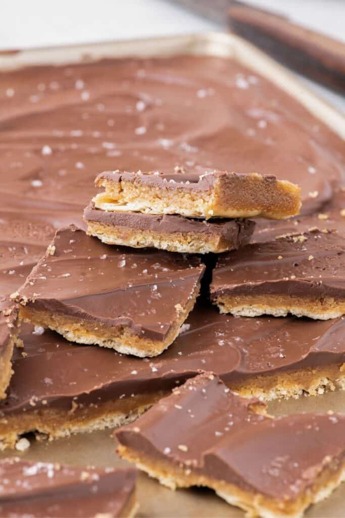 Saltine cracker toffee piled up on a baking sheet.