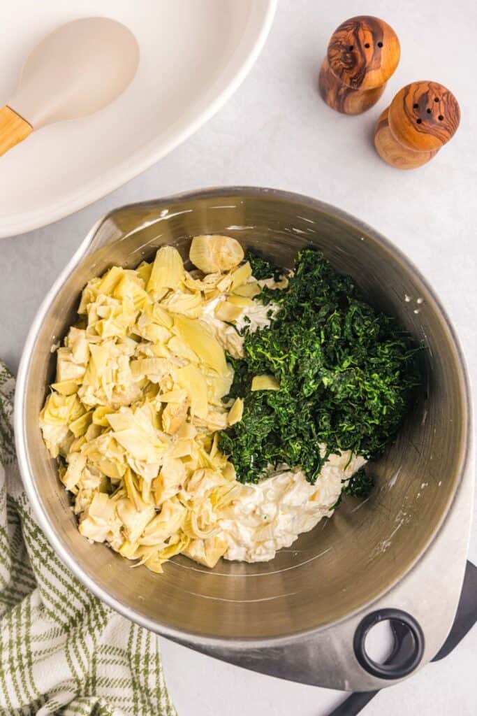 All ingredients for spinach artichoke dip combined in a large mixing bowl.