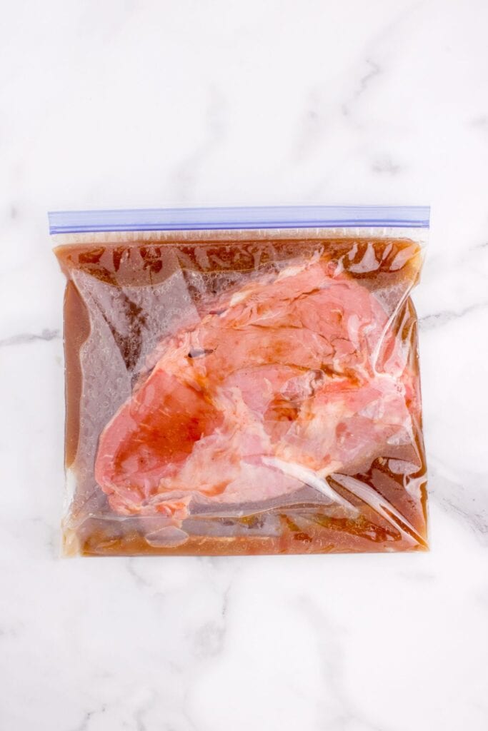 Round steak in a marinade in a zip top bag.