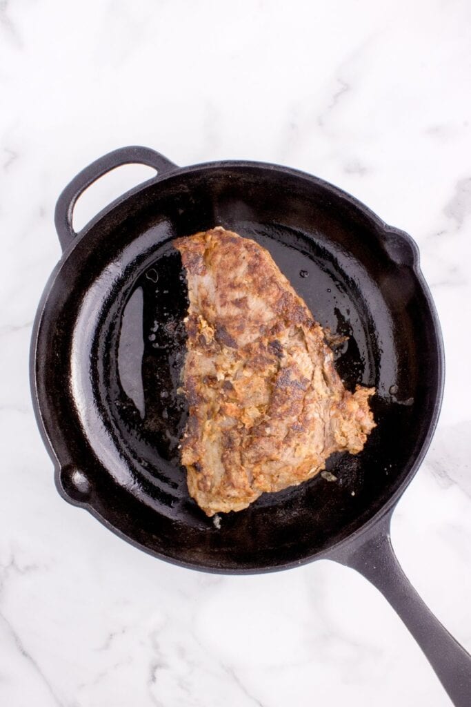 Round steak in a cast iron pan.