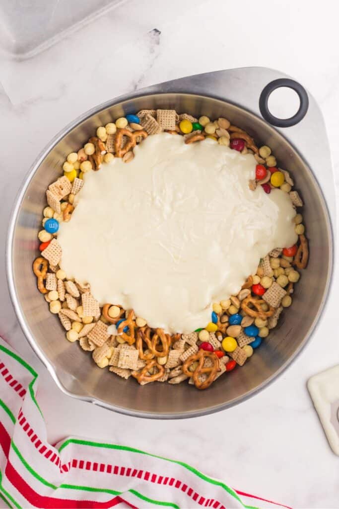 White chocolate being poured on top of the dry ingredients to make a white trash recipe.