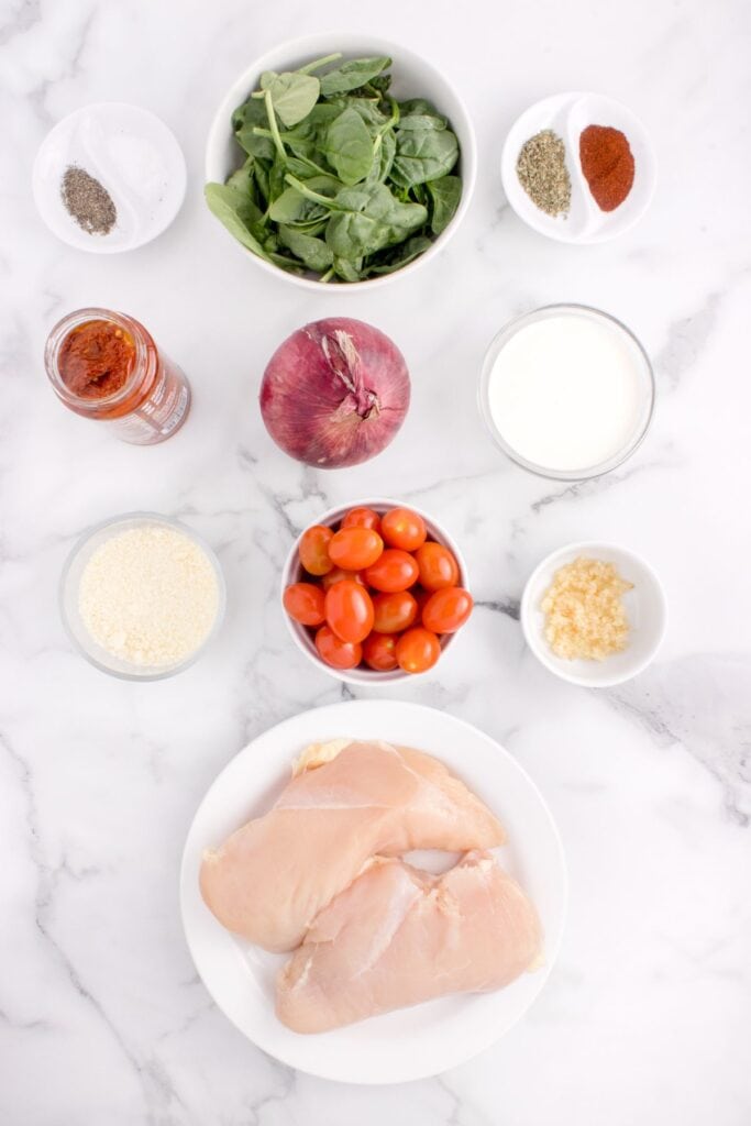 Ingredients for Tuscan Chicken: Chicken breasts, sun-dried tomatoes in oil, Italian seasoning, salt and pepper, paprika, onion, garlic, parmesan, baby spinach, cherry tomatoes, heavy whipping cream.