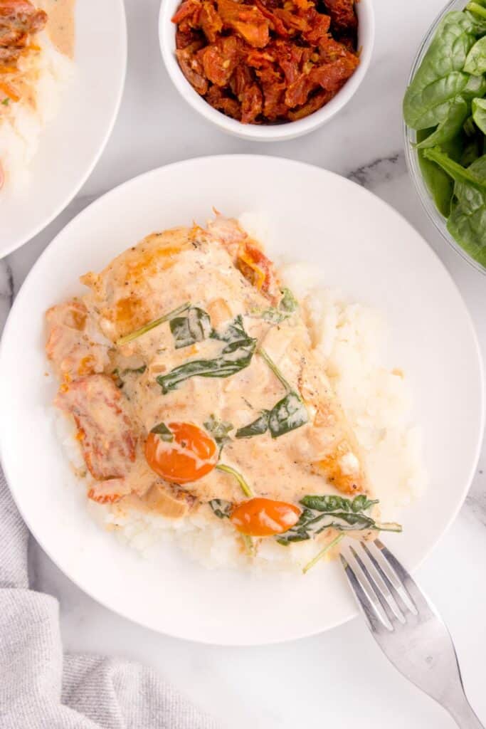 Overhead view of completed chicken dish on top of a bed of mashed potatoes.