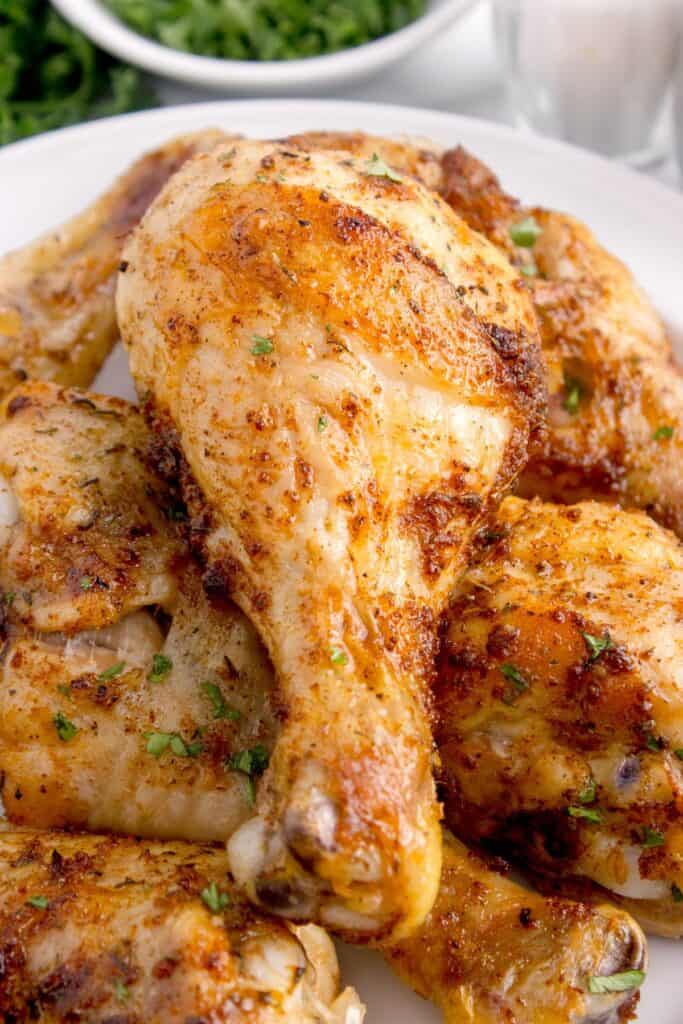 Close up image of a baked chicken leg sprinkled with parsley.