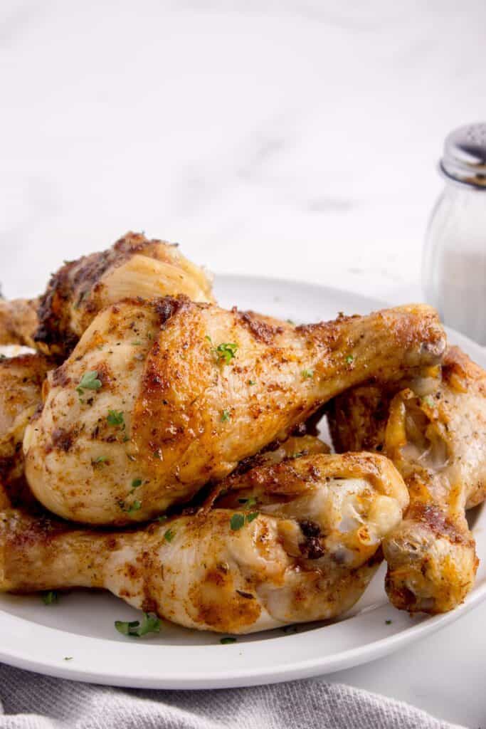 White serving plate with finished baked chicken legs on it.