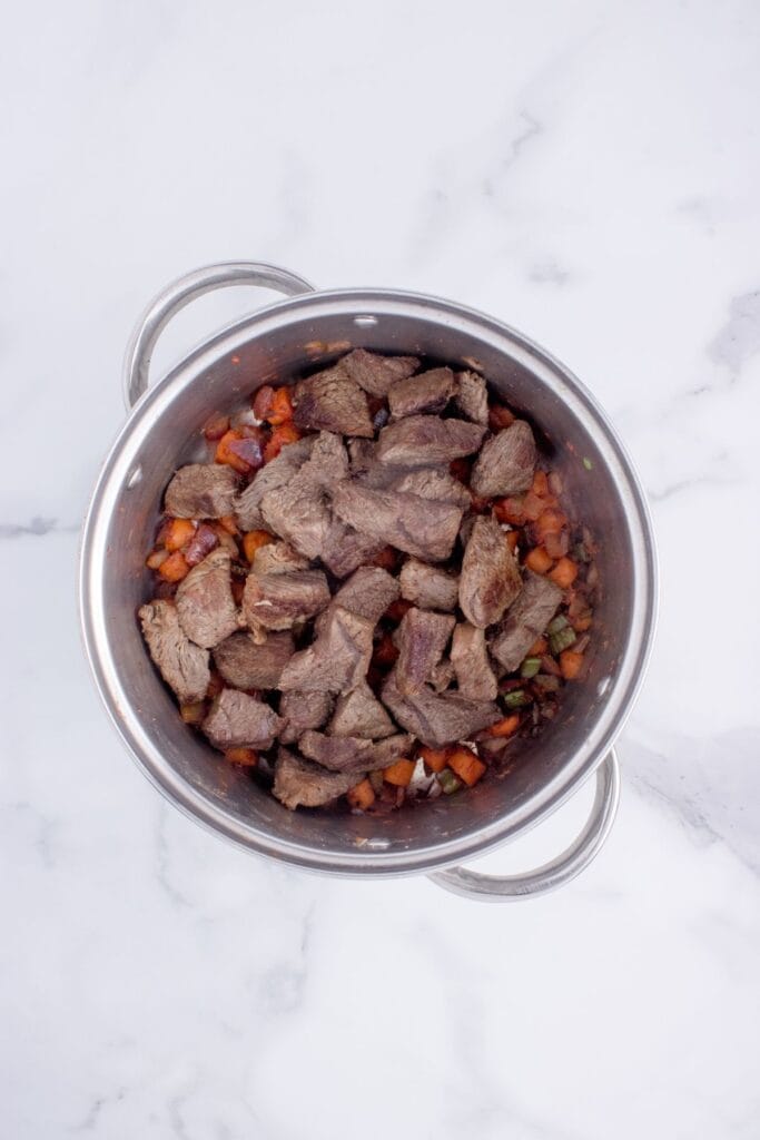 Sauteed stew meat and veggies in a pot.