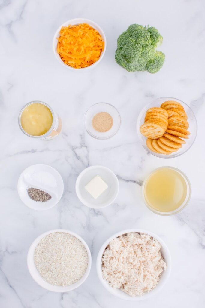 Ingredients for chicken broccoli rice casserole: long-grain white rice, chicken broth, shredded chicken, broccoli, sharp cheddar cheese, cream of chicken soup, garlic powder, salt, black pepper, Ritz crackers, and butter.