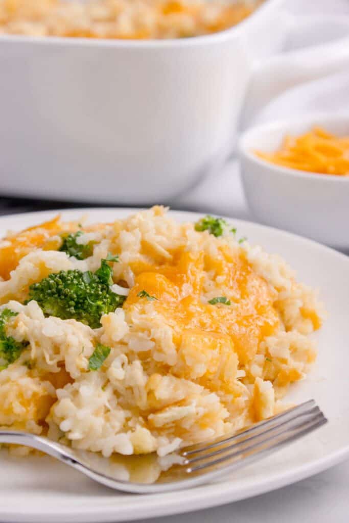 White dinner plate with finished chicken broccoli rice casserole and a fork on it.