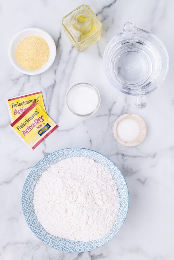 Ingredients for easy pizza crust: water, sugar, active dry yeast, flour, salt, olive oil, and cornmeal