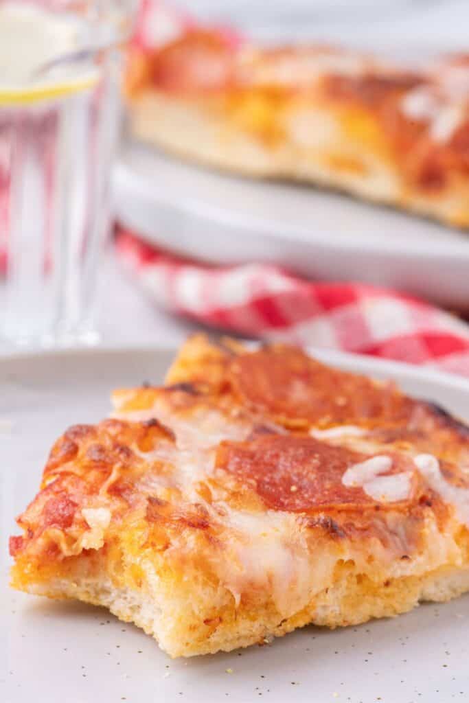 Baked pizza with a bite out of it to show texture of pizza crust.