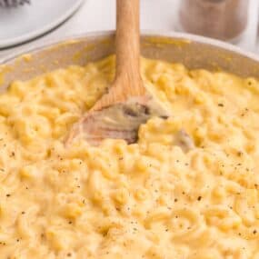 Large skillet with finished gouda mac and cheese recipe and a wooden spoon.