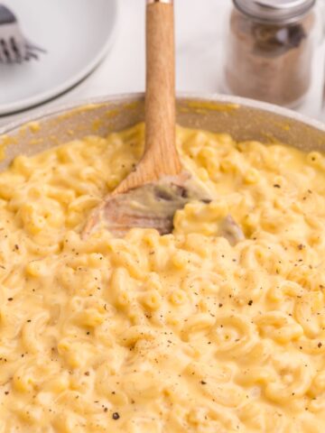 Large skillet with finished gouda mac and cheese recipe and a wooden spoon.