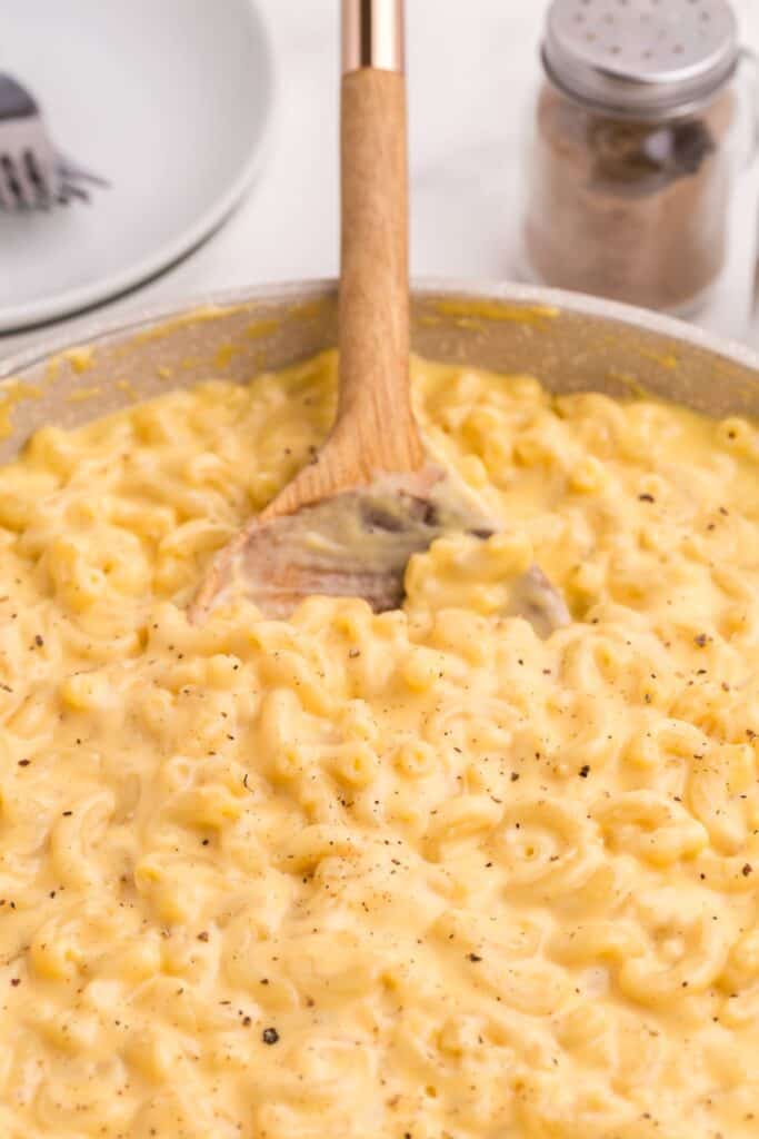 Large skillet with finished gouda mac and cheese recipe and a wooden spoon.