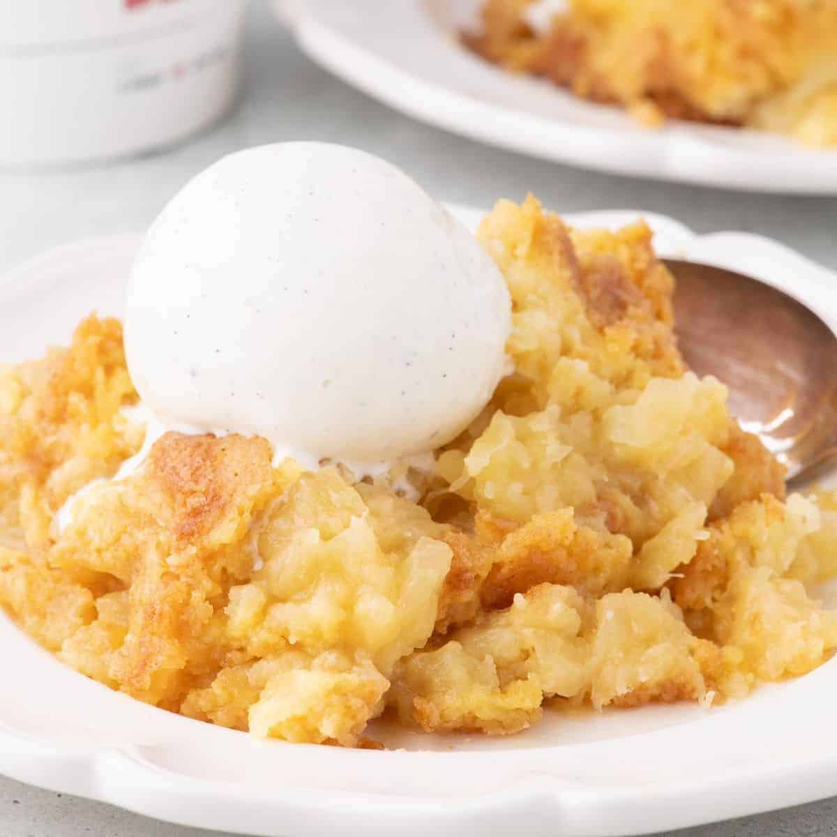 Pineapple Dump Cake on a plate with vanilla ice cream.