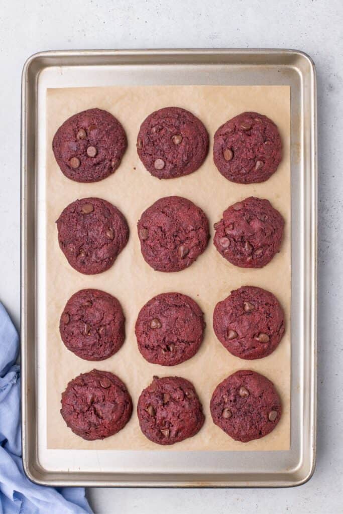 Baked red velvet cookies on a parchment lined baking sheet.