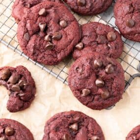 Pile of cookies sitting on a cooling rack and parchment paper.